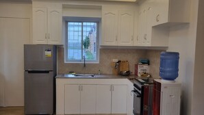 Een keuken met witte kastjes, een roestvrijstalen koelkast, een fornuis en een waterdispenser.
