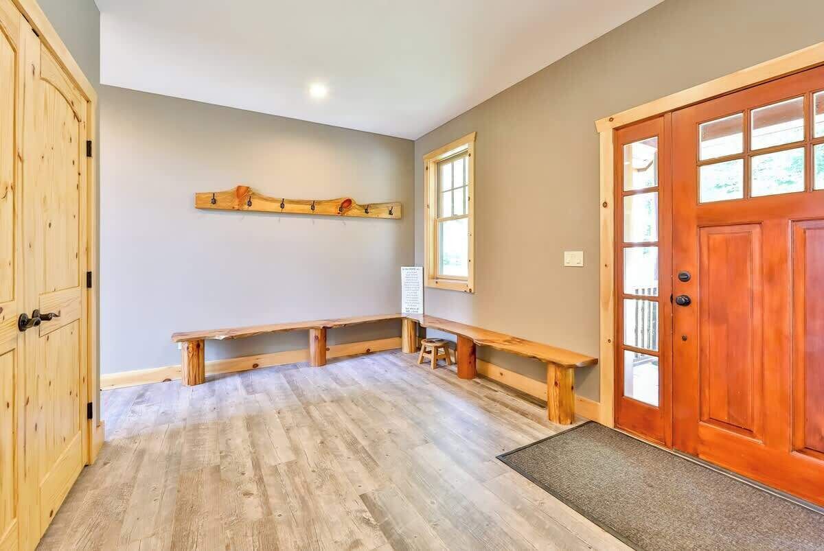 A room with a wooden bench, a wooden door, and a window.