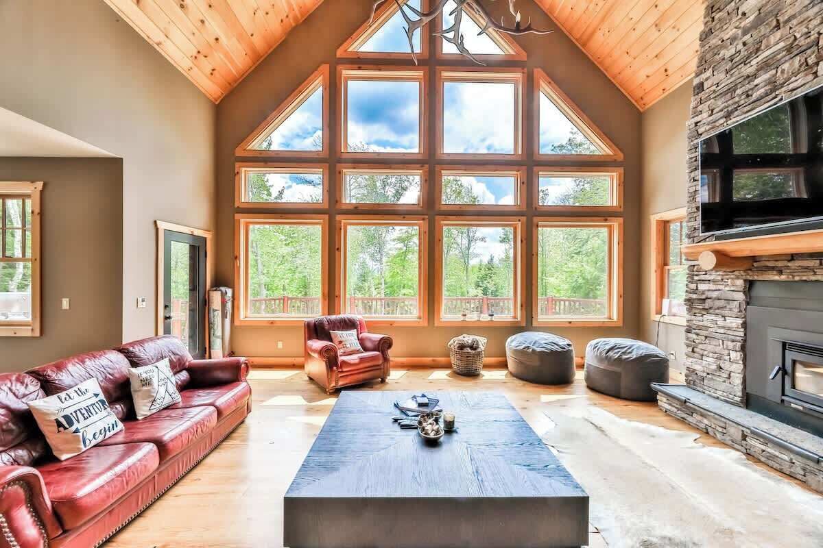 Un salon spacieux avec un plafond haut, de grandes fenêtres, une cheminée et un canapé en cuir.