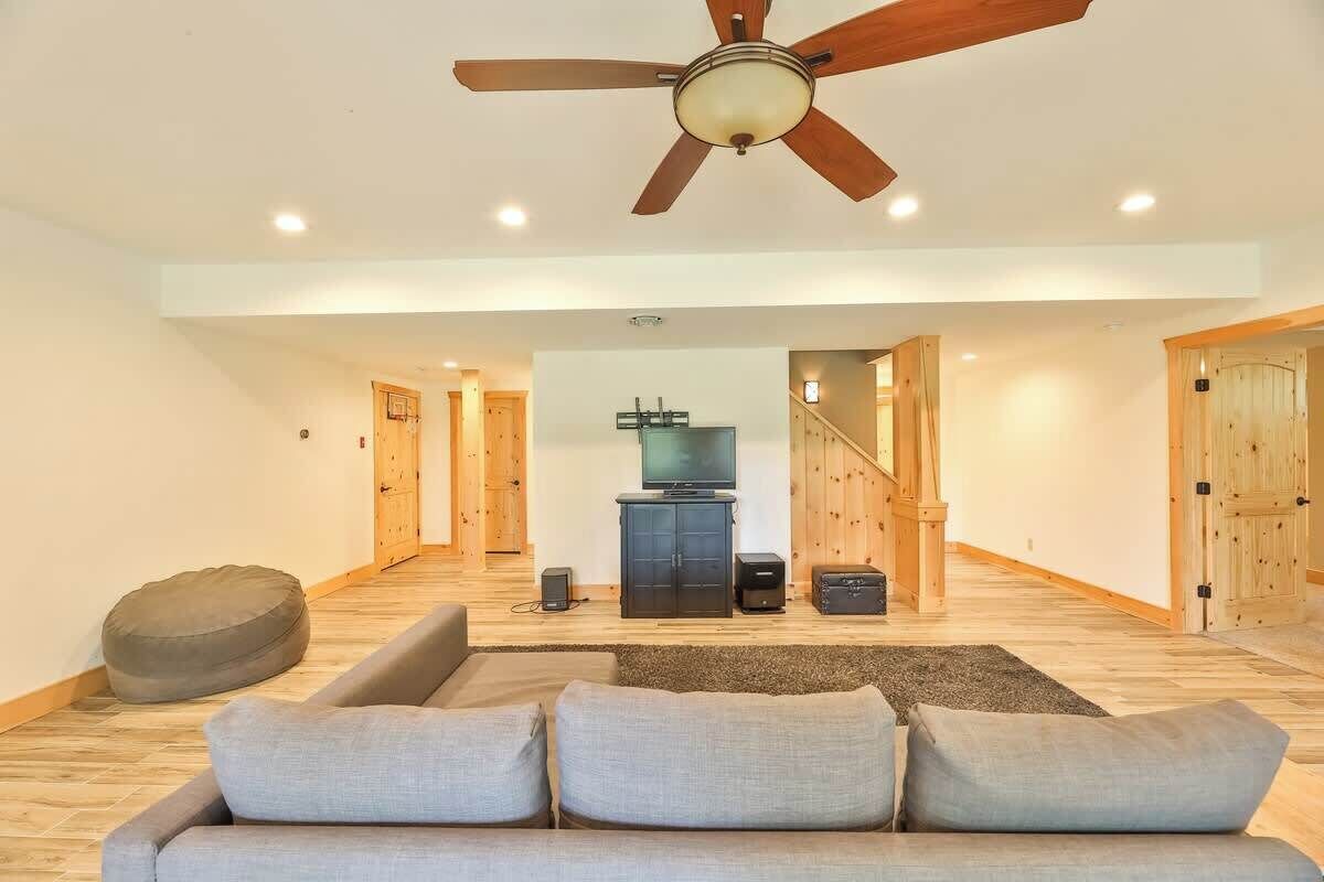 A spacious living room with a ceiling fan, a sofa, a television, and a staircase leading to another level.
