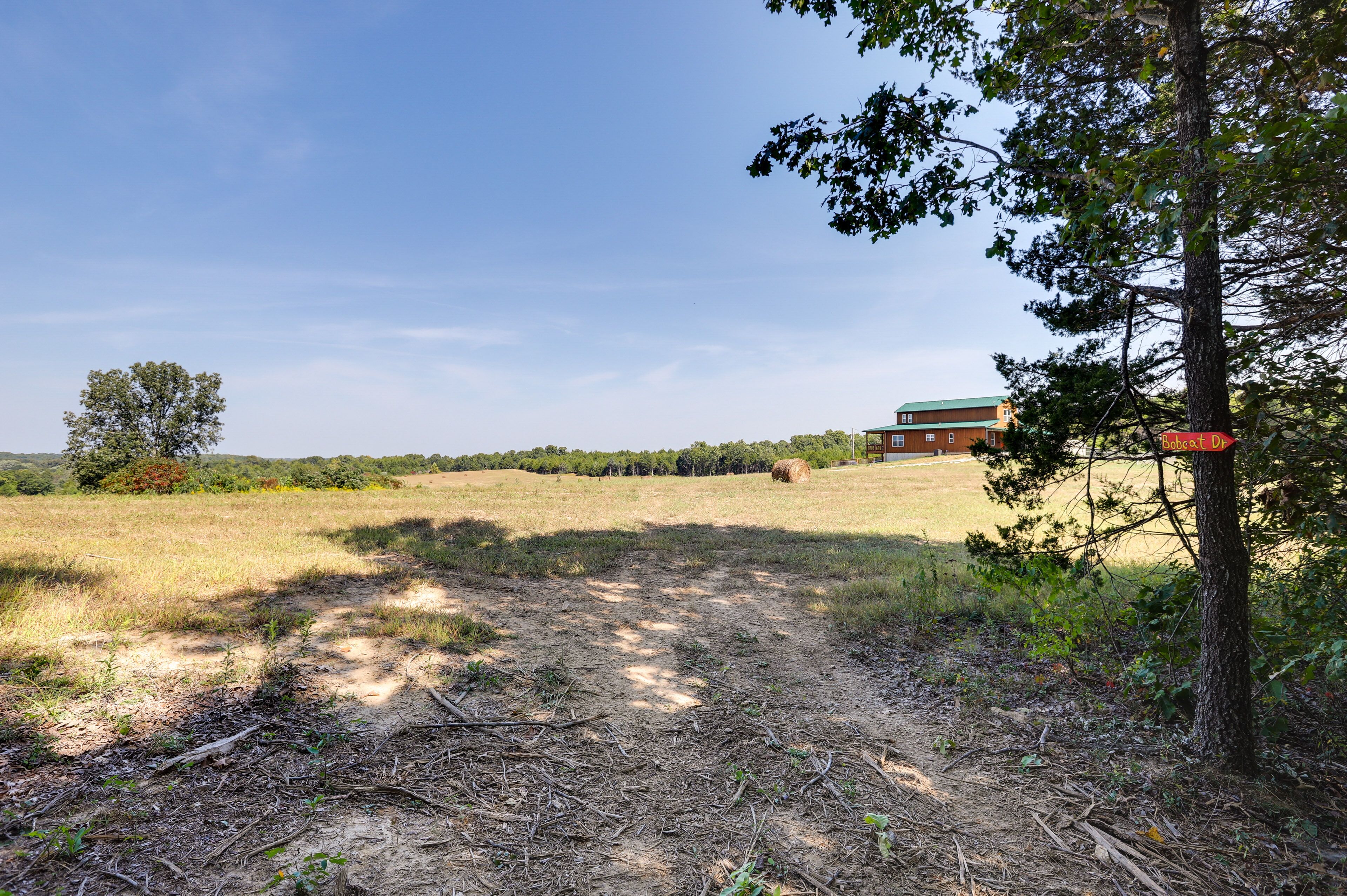 Ländliche Landschaft mit einem Feldweg, der zu einem Gebäude mit grüner Dachbegrünung führt.