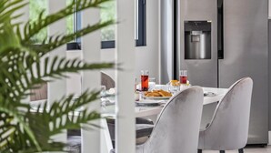 A modern dining area with a table set for two, a water dispenser, and a view of the outdoors. - Landscape View by Homie (Ponta do Sol)