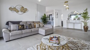 A modern living room with a grey sectional sofa, a marble coffee table, and a kitchen in the background. - Landscape View by Homie (Ponta do Sol)