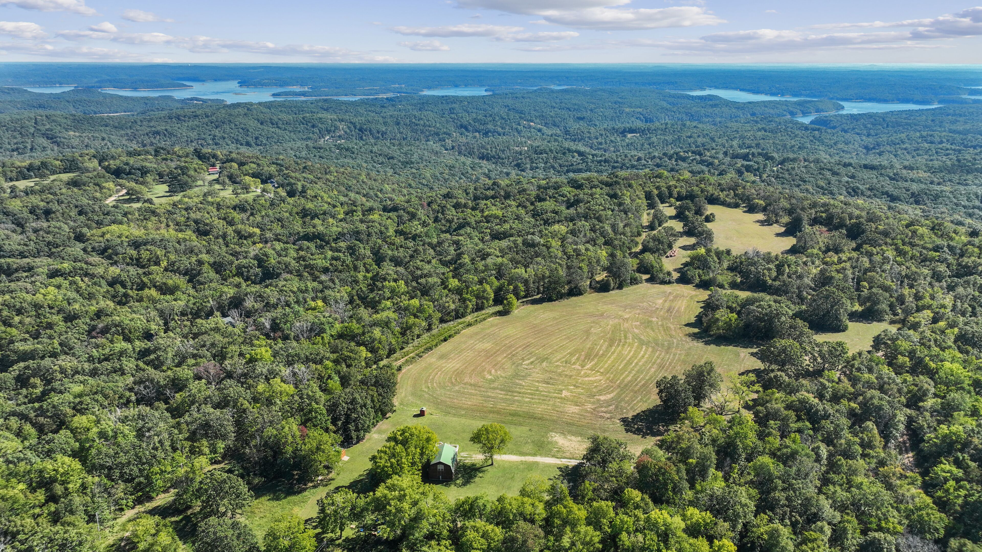 An aerial view of a forested area with a clear field and a small building.