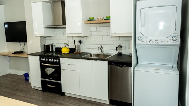 Una cocina moderna con armarios blancos, estufa, fregadero y lavavajillas.