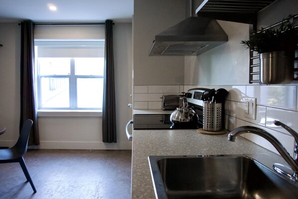 Una cocina moderna con un lavamanos de acero inoxidable, un hervidor y un tostador.