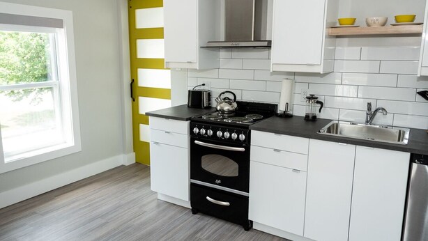 Een moderne keuken met witte kasten, een zwarte kookplaat en een roestvrijstalen spoelbak.