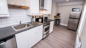 Une cuisine moderne avec des armoires blanches, un évier en acier inoxydable, une cuisinière et un réfrigérateur.