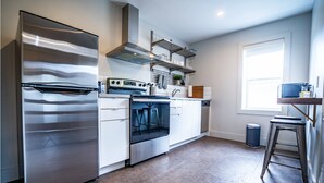 Una cocina moderna con electrodomésticos de acero inoxidable, armarios blancos y un ventanal que proporciona luz natural.
