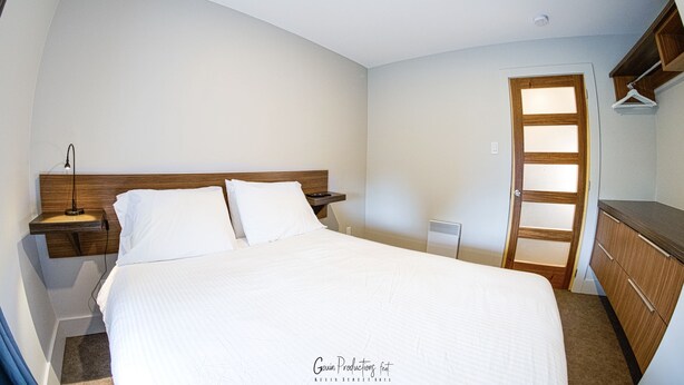Un dormitorio con cama, mesita de noche y cabecero de madera.