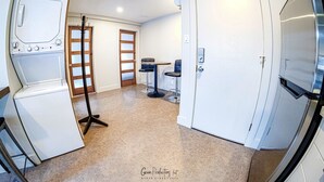 Una cocina compacta con lavadora, una mesa de comedor con sillas y un refrigerador.