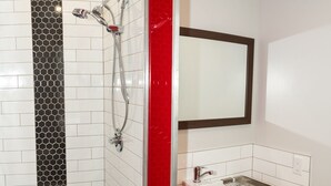 Un baño moderno con ducha, lavamanos y espejo.