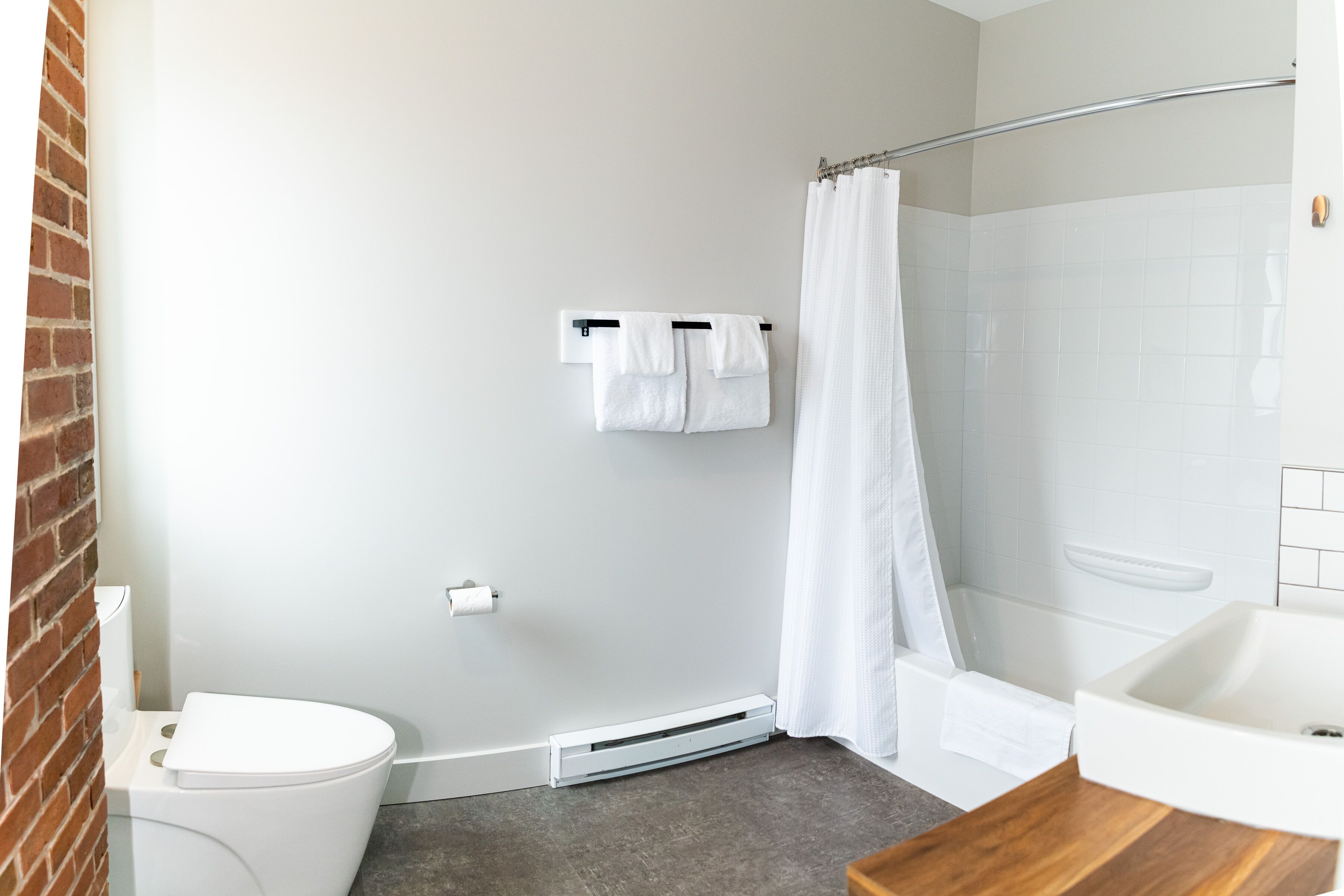 A bathroom with a toilet, a shower, a sink, and a towel rack.
