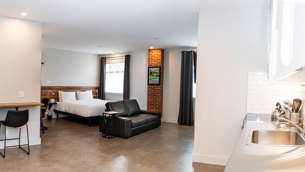 Ein kleines Hotelzimmer mit Küchenzeile, einem Bett, einer Schlafcouch und einer kleinen Essecke.