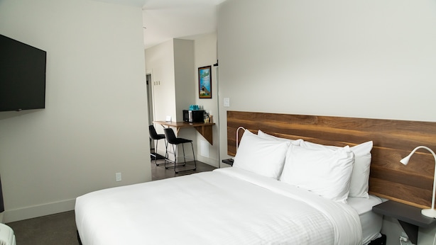 Habitación de hotel con una cama grande, un escritorio y una televisión montada en la pared.
