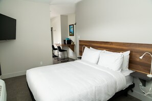 Habitación de hotel con una cama grande, un escritorio y una televisión montada en la pared.