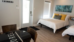 Une chambre d’hôtel avec un lit, une petite table et une chaise. Il y a une porte et une fenêtre.
