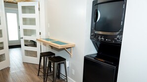 Une cuisine compacte équipée d’un four à micro-ondes, d’une petite table en bois et de deux tabourets.