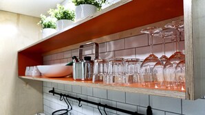 Una estantería en la cocina con cristalería y una tetera.