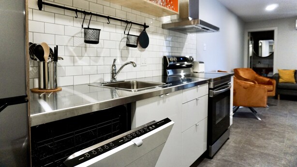 Una cocina moderna con electrodomésticos de acero inoxidable, armarios blancos y lavavajillas integrado.