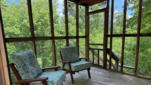 A wooden deck with two patterned chairs and a wooden railing. - Roundhouse Cabin in Pigeon Forge …in town  (Pigeon Forge)