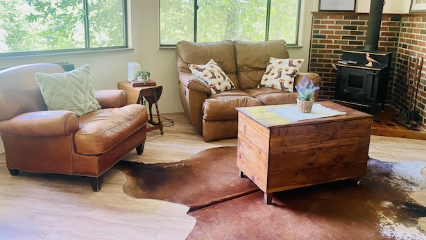 A cozy living room with leather sofas, a wooden coffee table, and a brick fireplace. - Roundhouse Cabin in Pigeon Forge …in town  (Pigeon Forge)