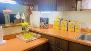 A kitchen with wooden cabinets, a countertop, a book titled 'The Complete Cookbook', and yellow flower-patterned containers. - Roundhouse Cabin in Pigeon Forge …in town  (Pigeon Forge)