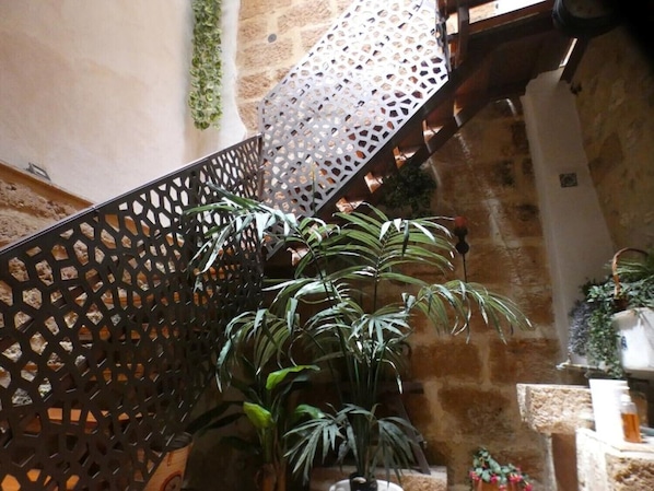 Eine Treppe mit schwarzer Metallreling und Blumentöpfen.