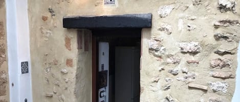 A stone building with a black door frame and a sign above the door.