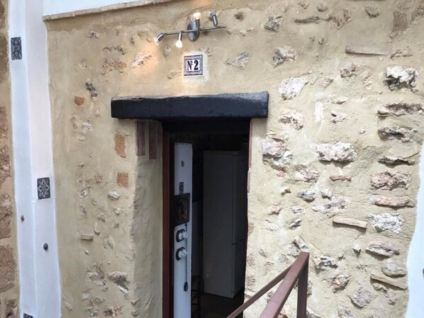 Ein Steinhaus mit schwarzem Türrahmen und einem Schild über der Tür.