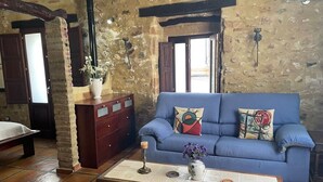 A rustic living room with a blue sofa, wooden coffee table, and a stone wall.