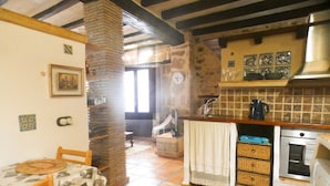 A cozy kitchen with a tiled backsplash, a wooden table with chairs, and a stone pillar.