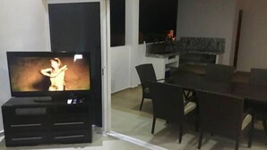 Een woonkamer met een televisie, een eettafel en stoelen.