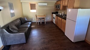 Une cuisine compacte avec des meubles en bois, un réfrigérateur blanc, un four à micro-ondes et une cuisinière. On y trouve une petite table à manger avec deux chaises.