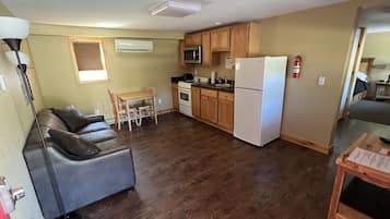 A compact living space with a kitchenette, a dining area with a table and chairs, a sofa, and a lamp.
