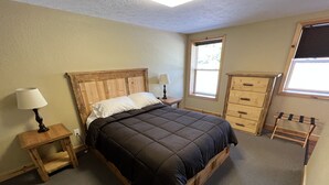 Un dormitorio con una cama de madera, mesitas de noche, un aparador y una ventana.