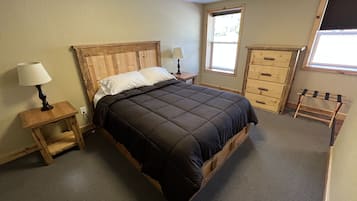 A bedroom with a wooden bed, bedside tables, a dresser, and a window.