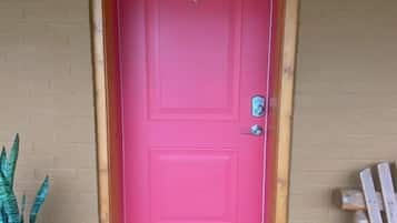 A pink door with the number 4, a potted plant, and a wooden bench.