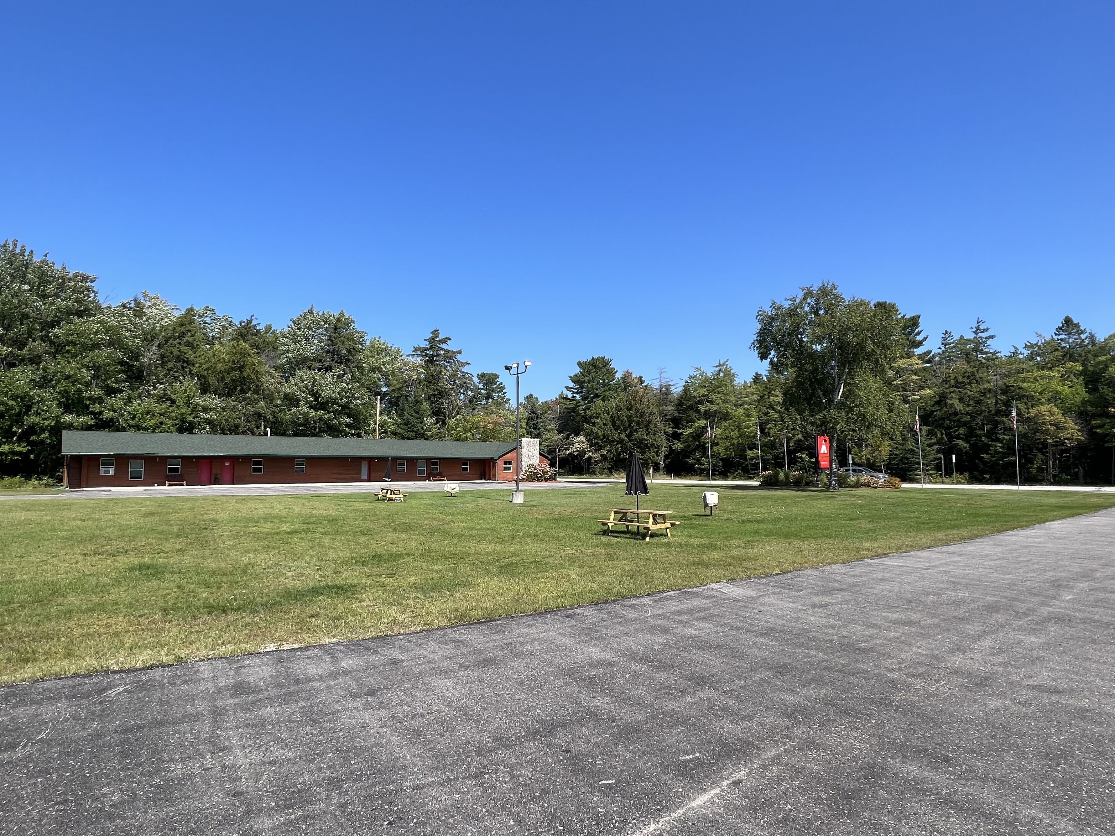 A red building with a green roof, a grassy field, and a paved road.