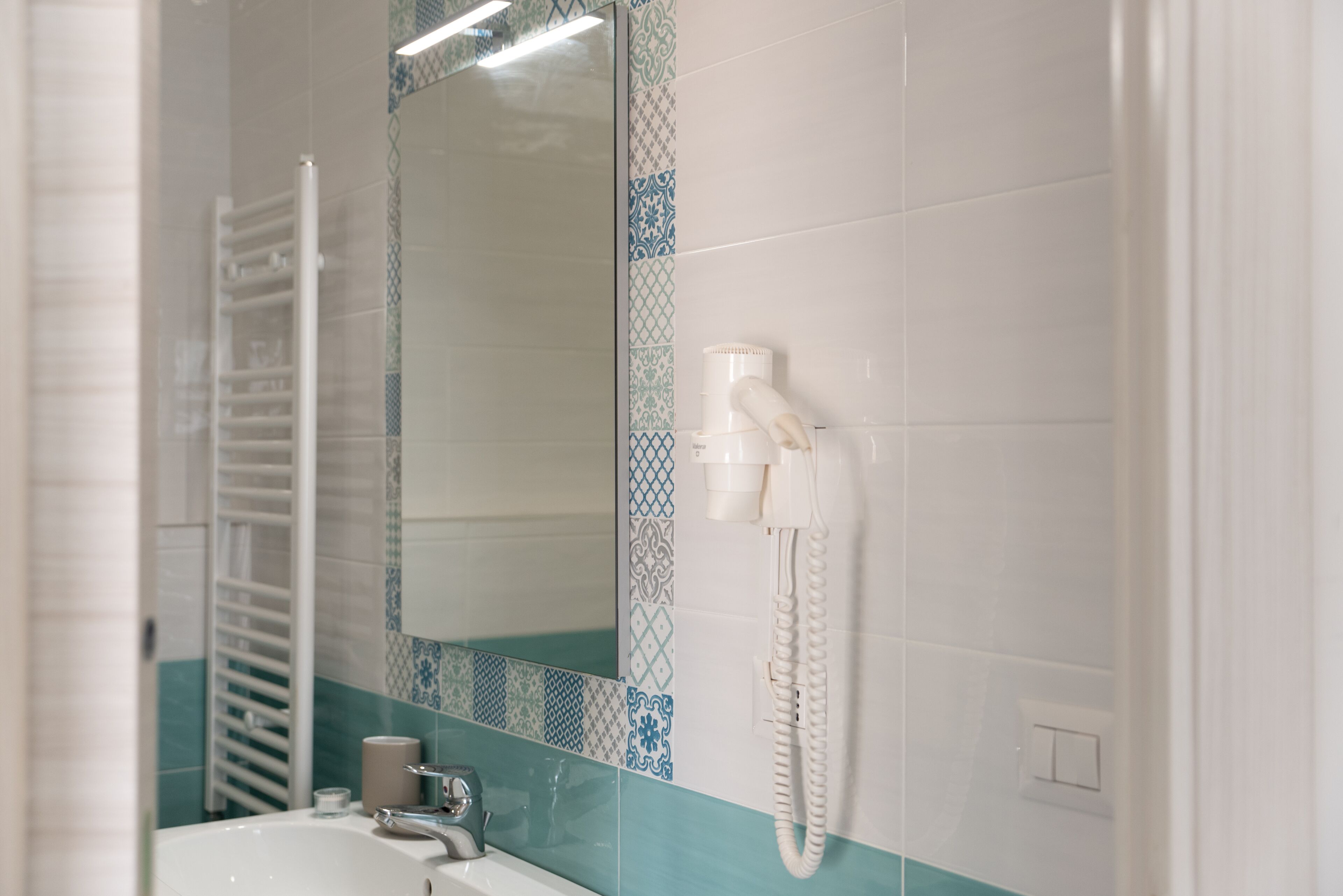 A bathroom with a white sink, a mirror, a towel rack, and a telephone.