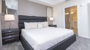 Een moderne slaapkamer met een groot bed, twee nachtkastjes en een inloopkast.