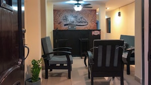 A reception area with a map-themed wall, a ceiling fan, and a reception desk. - Hostal Sin Fronteras (León)