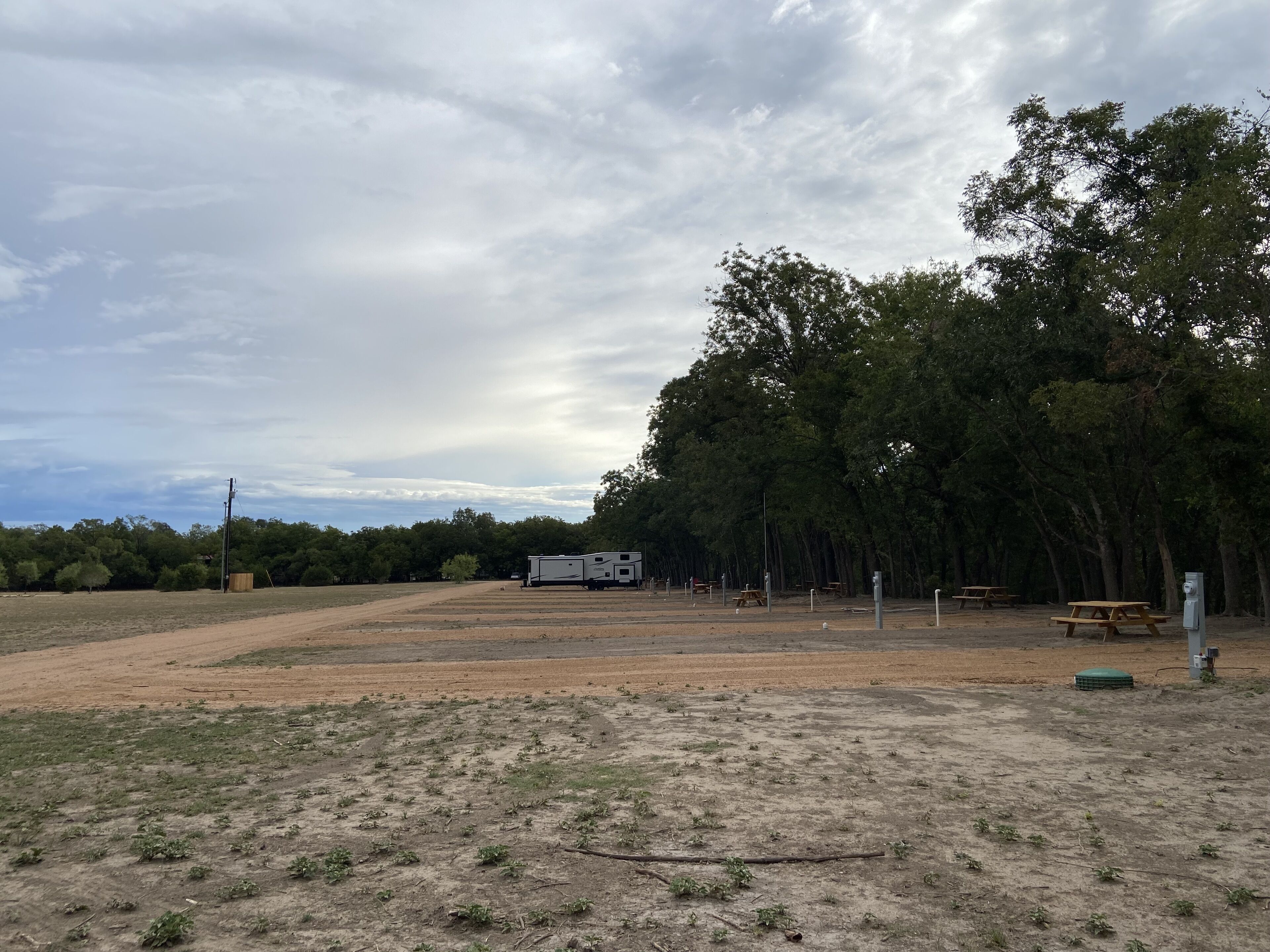 A campground with open fields, picnic tables, and a trailer.