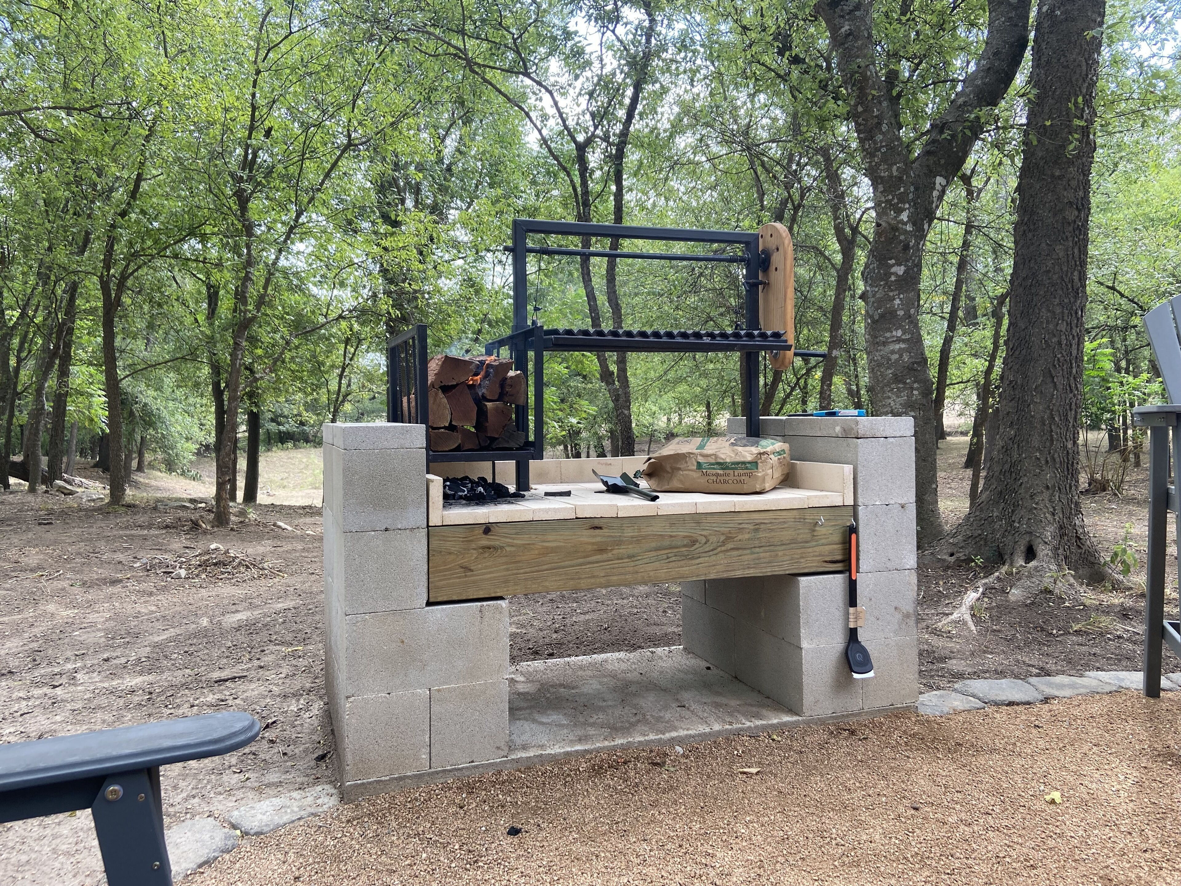 Un banc en béton doté d’une structure métallique, entouré d’arbres.