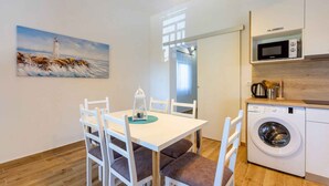 A modern kitchen with a washing machine, a microwave, and a painting of a lighthouse.