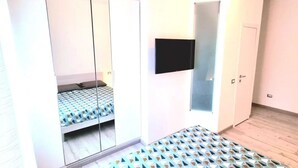 Ein Schlafzimmer mit einem Bett, einem Kleiderschrank und einem an der Wand befestigten Fernseher.