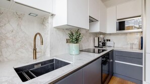 Una cocina moderna con salpicadero de mármol, electrodomésticos de acero inoxidable y muebles oscuros.
