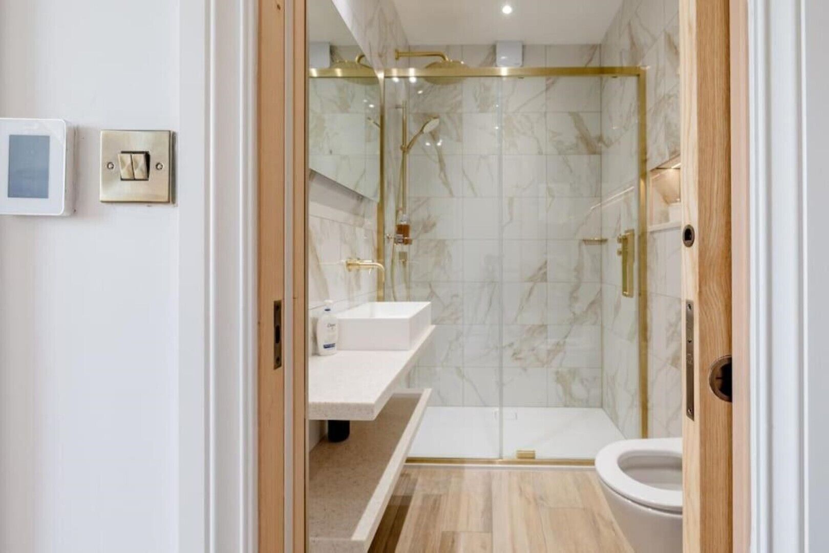 A modern bathroom with a glass-enclosed shower, a white sink, and a toilet.