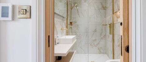 A modern bathroom with a glass-enclosed shower, a white sink, and a toilet.