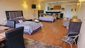 A hotel room with two beds, a dining area, and a kitchenette.